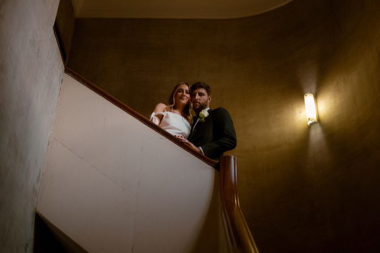 Low light wedding photo of couple in stairwell by Alex Carlyle Photography