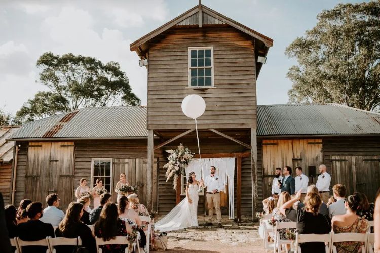 Outdoor wedding ceremony with farm building backdrop at Belgenny Farm
