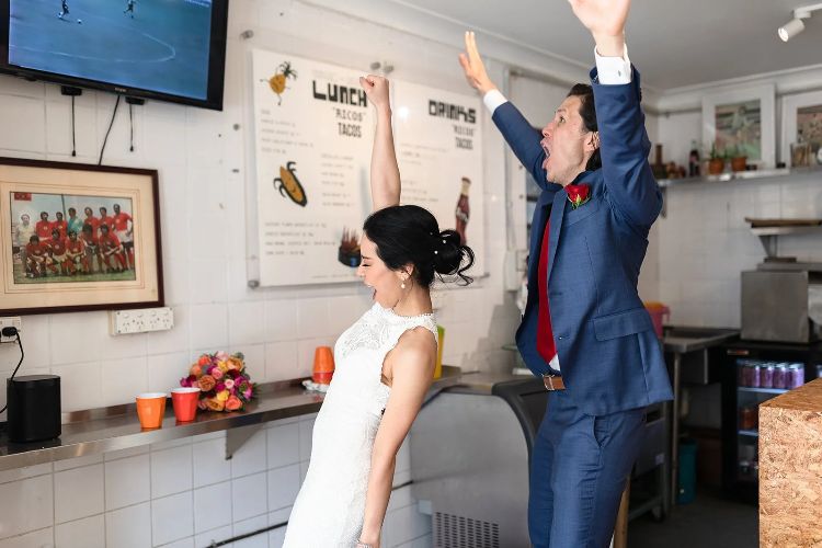 Documentary wedding photo with couple celebrating near TV by Carlita Sari
