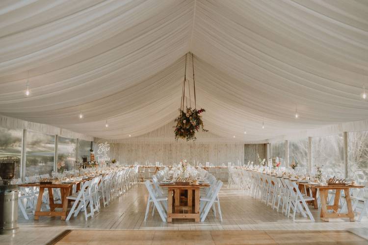 Rustic wedding marquee with long timber reception tables at Growwild