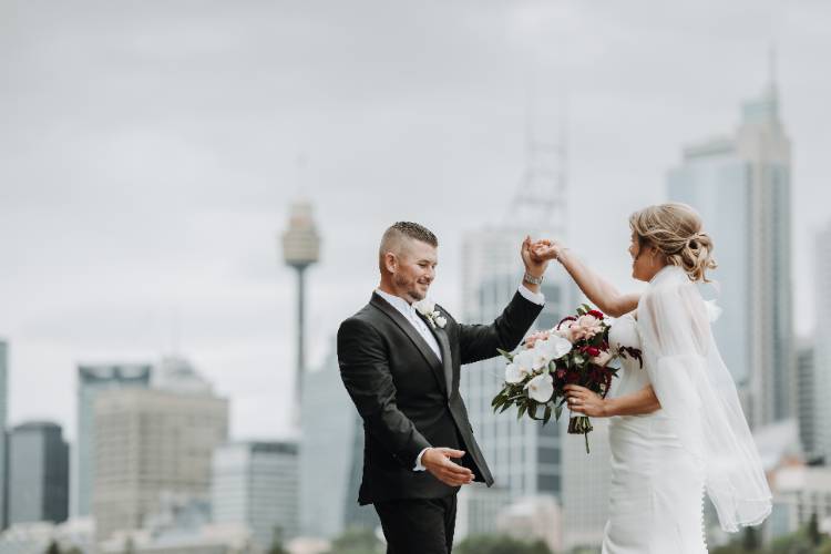 Joyful wedding photo of newlyweds with Centrepoint Tower by Ben Newnam