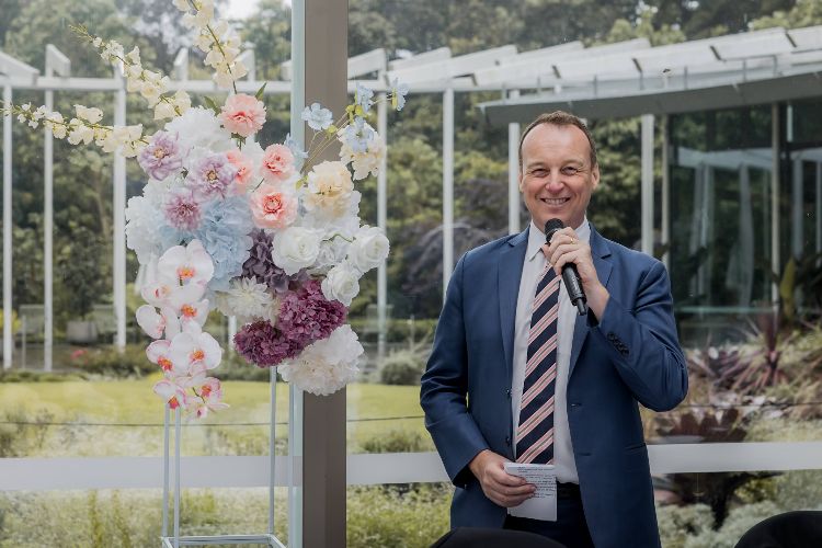 Chris Stedman, Sydney celebrant and MC, holding a microphone and smiling